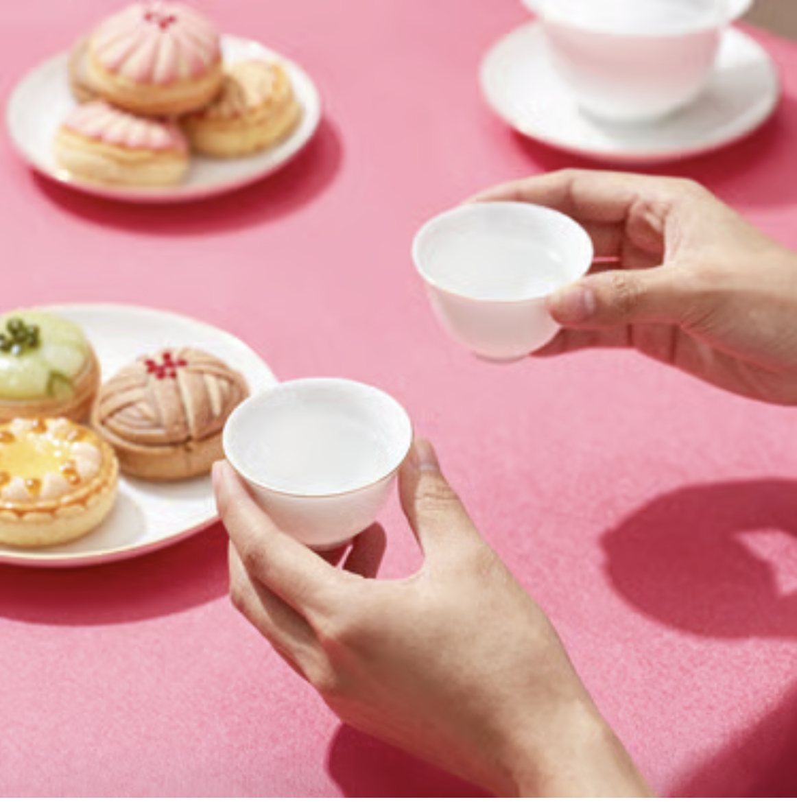 A teacup passing from one pair of hands to another